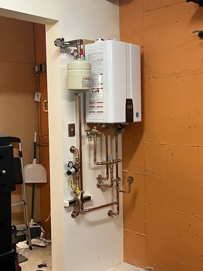 Plumbing technician inspecting water heater connections in Stillwater